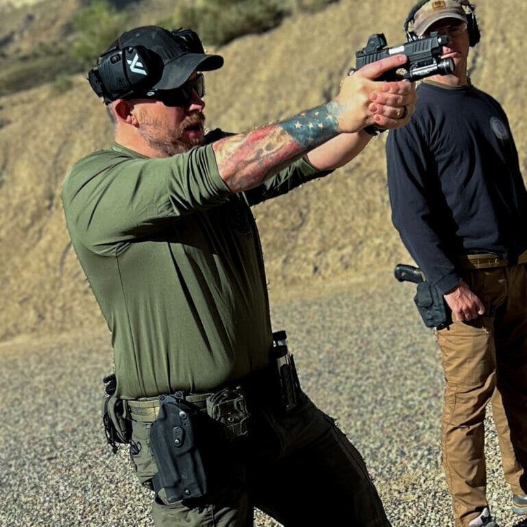 A man in black shirt holding a gun.