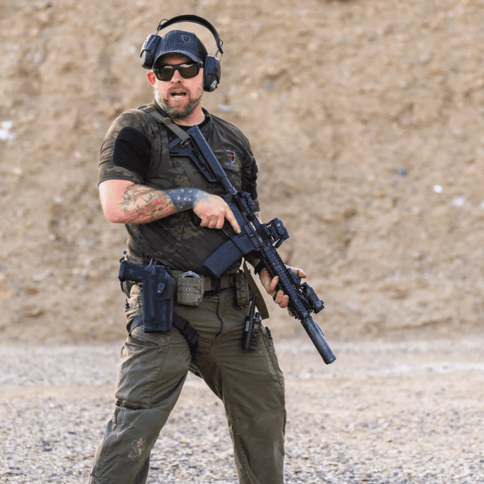 A man holding a rifle while wearing headphones.